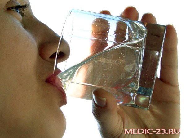 Девушка запивает капсулу водой