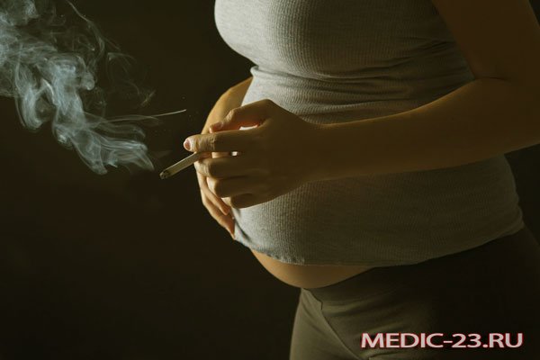 Беременная женщина курит сигарету